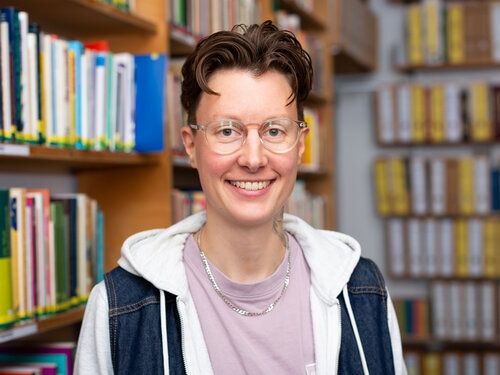 Auf dem Portrait ist Lara Ledwa vor einem Bücherregal zu sehen.